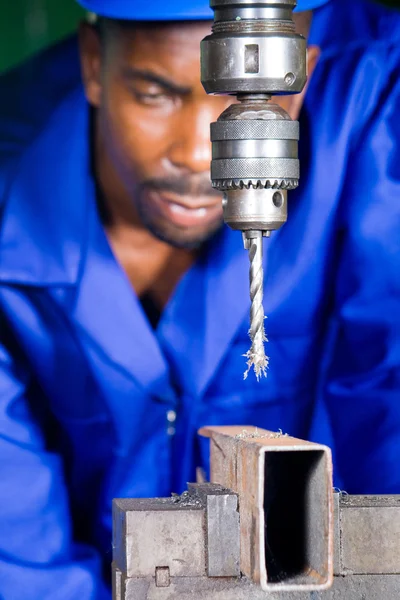 Trabalhador de colarinho azul africano em oficina trabalhando na máquina de perfuração — Fotografia de Stock