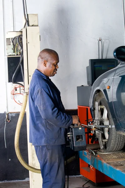 African mechanic working on a vehicle wheel alignment — Stock Photo, Image