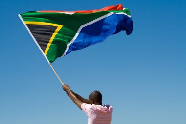 African man waving a south african flag against blue sky clipart