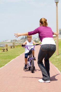 mutlu küçük kız annesine doğru bisiklet sürmek