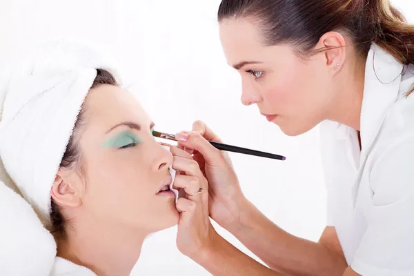 Professional female makeup artist applying makeup to model's face — Stock Photo, Image