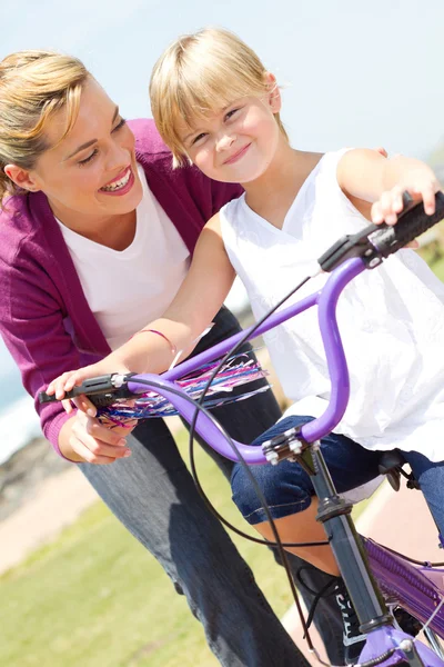 Mère heureuse enseignant à sa petite fille comment faire du vélo — Photo