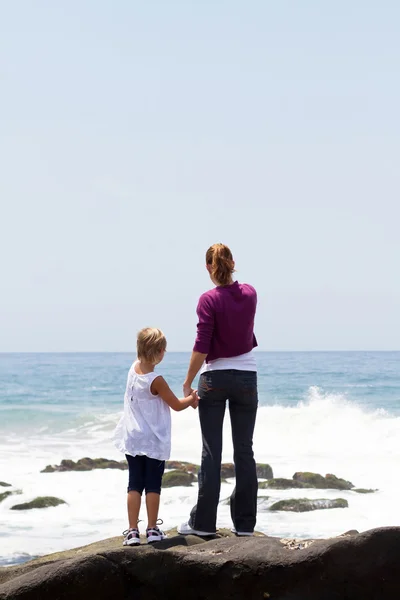 母と娘のビーチの岩の上に立っているの背面図 — ストック写真