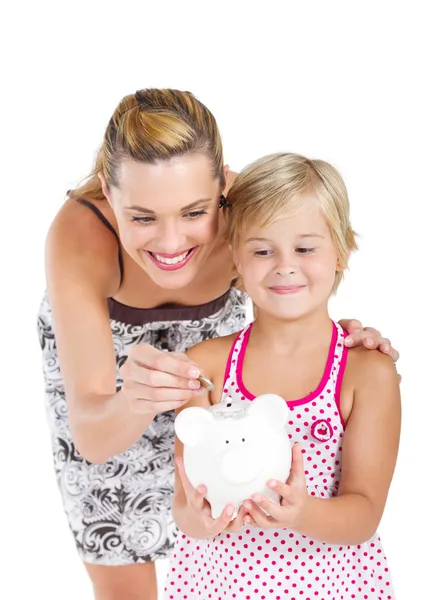 Happy mother putting coins into her daughter's piggybank — Stock Photo, Image