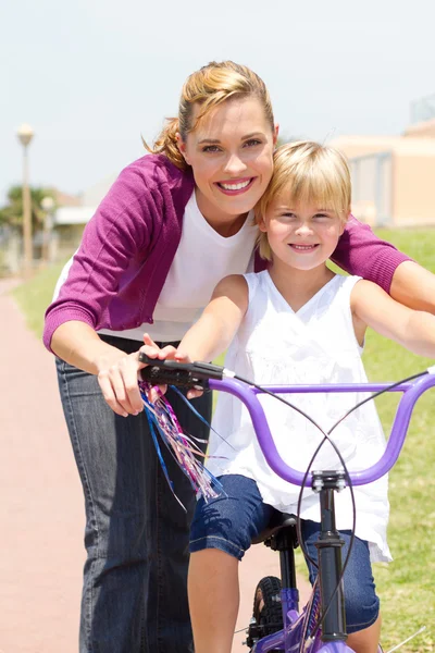 Happy mother teaching little daughter how to ride a bicycle Stock Image