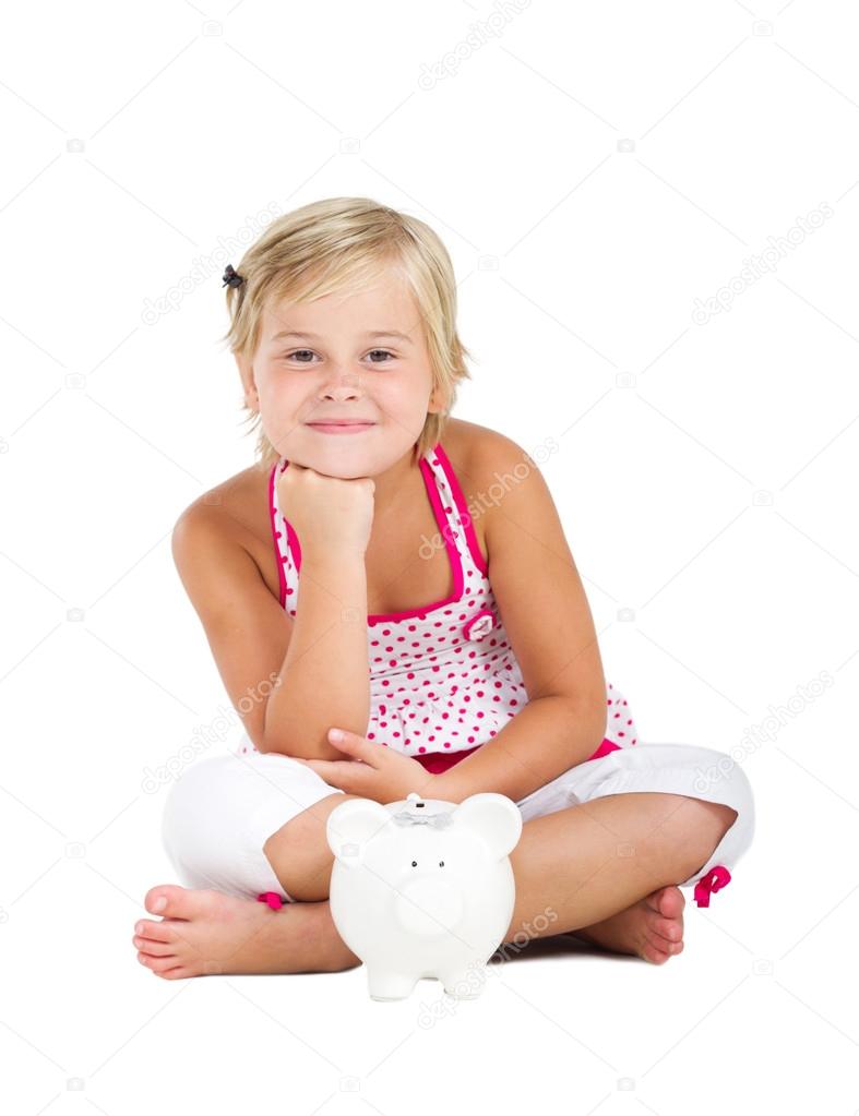 Happy little girl sitting on floor with piggy bank