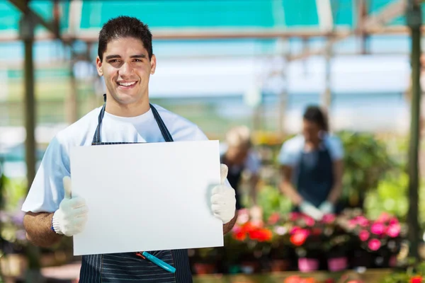 Glücklicher Gärtner hält weiße Tafel im Gewächshaus — Stockfoto