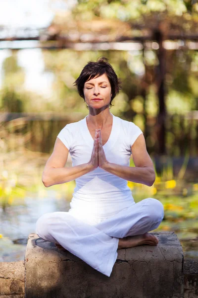 Mulher de meia-idade fazendo meditação na lagoa — Fotografia de Stock