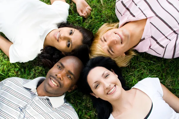 Groep van jonge diversiteit liggen op gras — Stockfoto