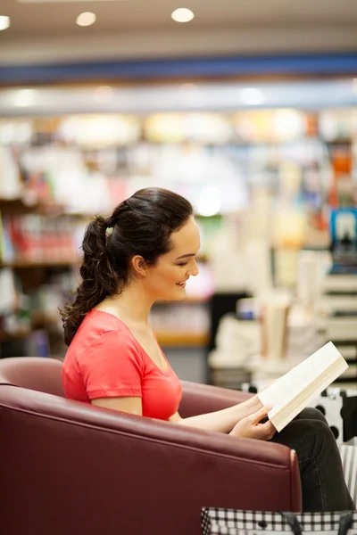 Young woman reading a book in bookstore — Stock Photo, Image