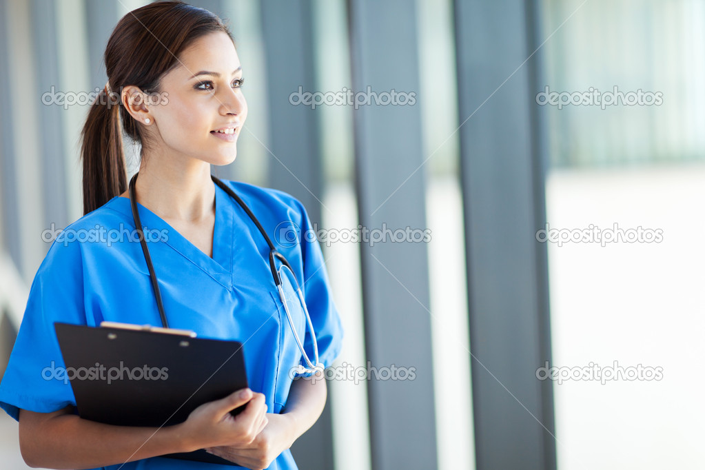Beautiful young female medical intern looking outside window