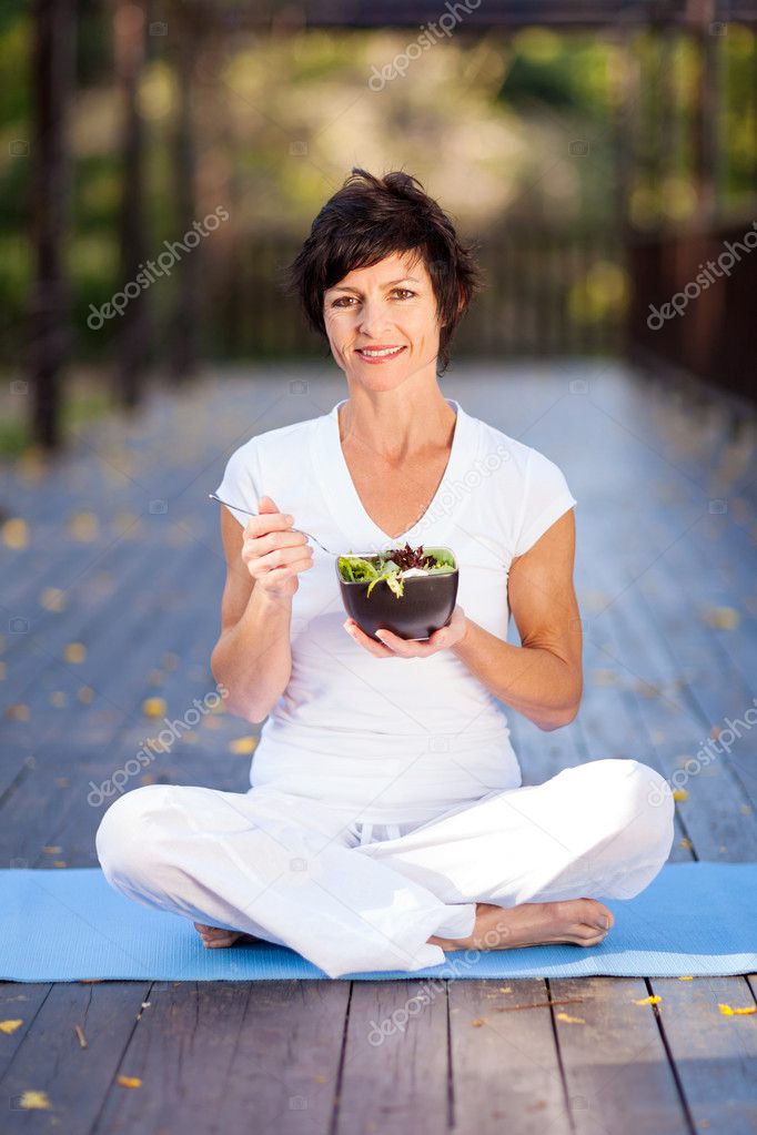Healthy middle aged woman eating salad outdoors