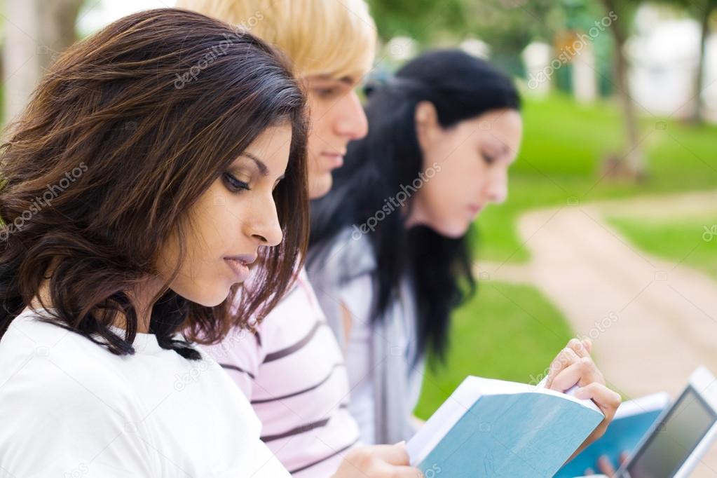 Group of college students reading book