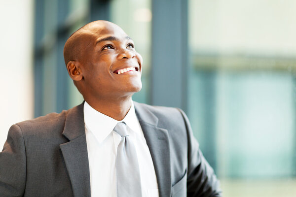 Optimistic african american businessman looking up