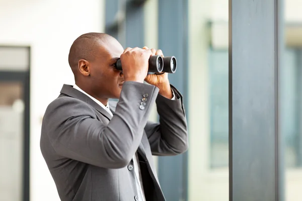 Decidido hombre de negocios afroamericano usando prismáticos en la oficina —  Fotos de Stock