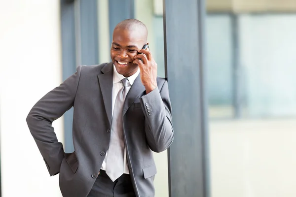 Gelukkig Afrikaans Amerikaans zakenman praten op mobiele telefoon in modern kantoor — Stockfoto