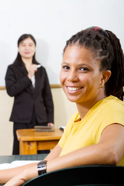 Estudiante adulto en el aula, fondo es profesor de pie junto a la pizarra blanca — Foto de Stock