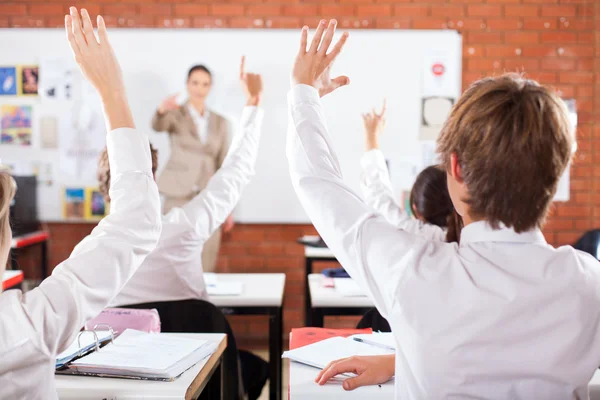 Groep van studenten armen omhoog in klas — Stockfoto