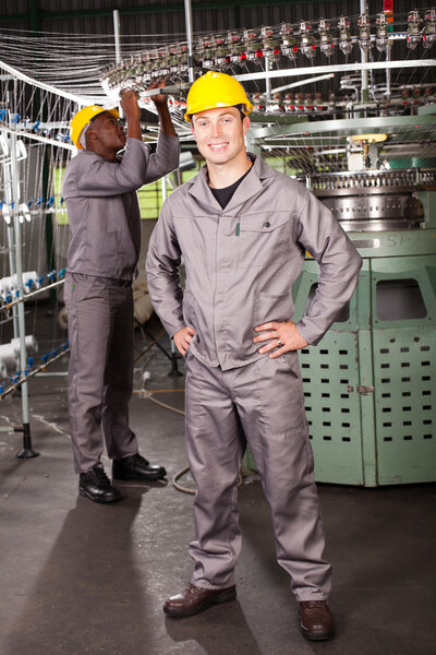 Портрет работника текстильной фабрики в полный рост перед машиной
