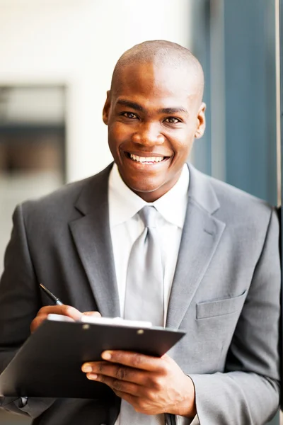 Smiling african american office worker writing report in office Stock Picture