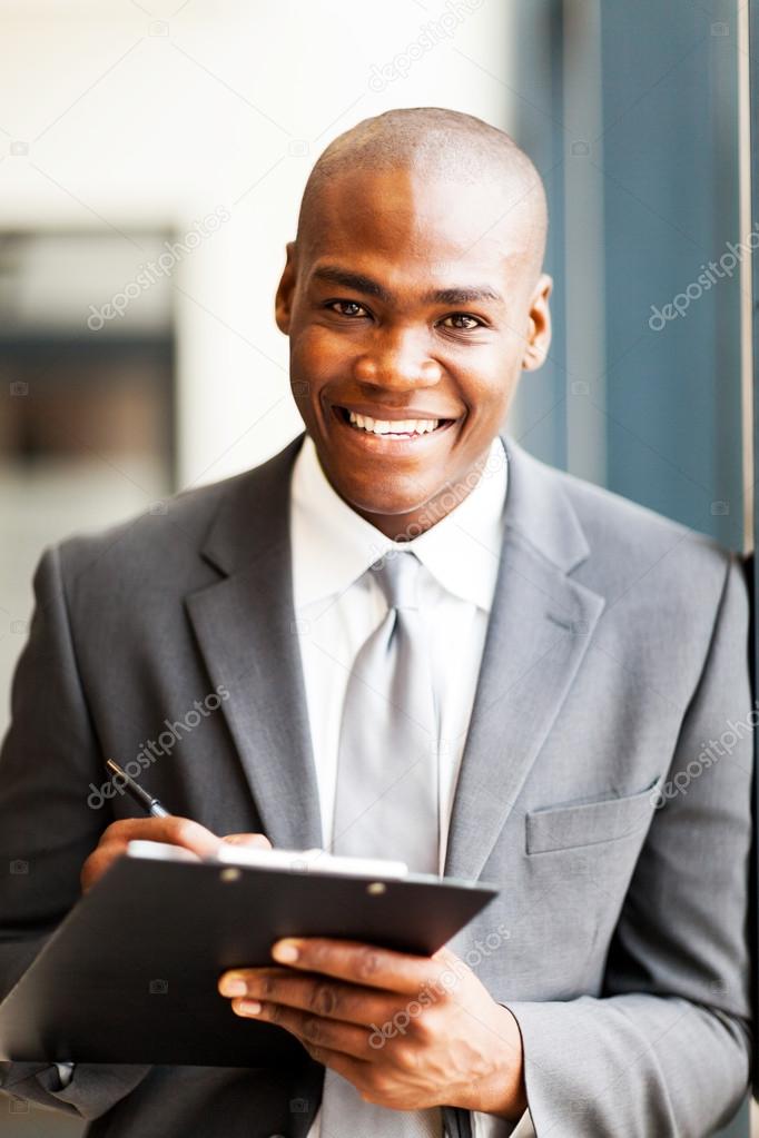 Smiling african american office worker writing report in office