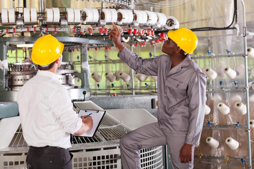 Textile factory manager and worker checking yarn on weaving machine