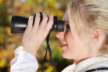 genç kadın sonbahar ormanda dürbün