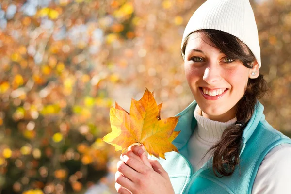 Feliz joven en el bosque de otoño sosteniendo hojas de árbol dorado — Foto de Stock