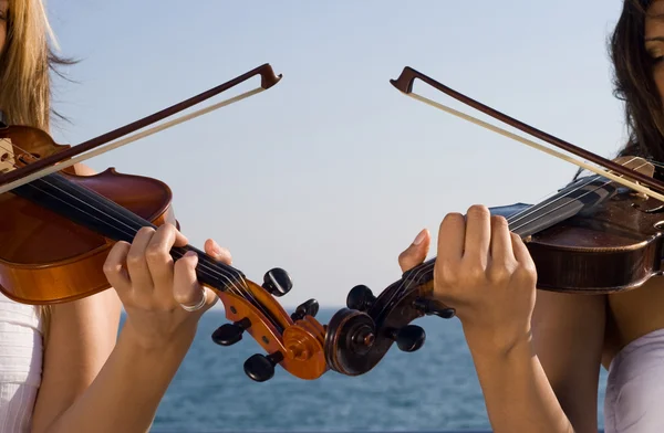 Two young women playing violin on beach — Stock Photo, Image
