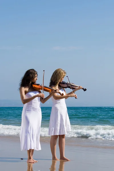 Two young female violinists playing violin on beach — Stock Photo, Image