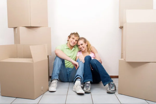 Happy young couple sitting on new home floor — Stock Photo, Image