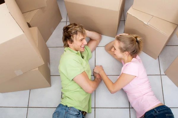 Happy young couple lying on their new home floor — Stock Photo, Image