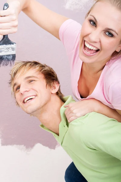 Joven pareja juguetona divertirse mientras que la pintura de nuevo hogar —  Fotos de Stock