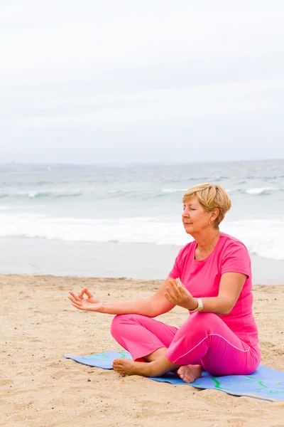 Friedliche Meditation einer Seniorin am Strand — Stockfoto