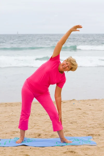 Felice donna anziana che si estende sulla spiaggia — Foto Stock