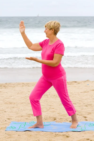 Здорова старша жінка вправа на пляжі — стокове фото