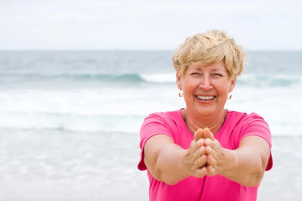 Gelukkig senior vrouw oefenen op strand — Stockfoto