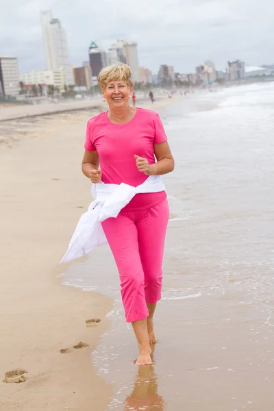 Happy senior woman running on beach — Stock Photo, Image