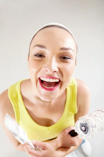 Laughing young woman with paintbrush and roller — Stock Photo, Image