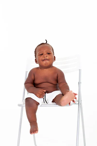 Милый африканский американский мальчик сидит на белом стуле — стоковое фото