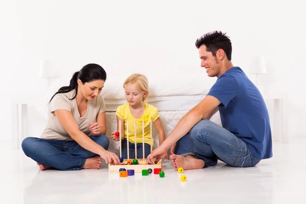 Familia feliz jugando juego de juguete con la hija en el piso del dormitorio Imágenes de stock libres de derechos