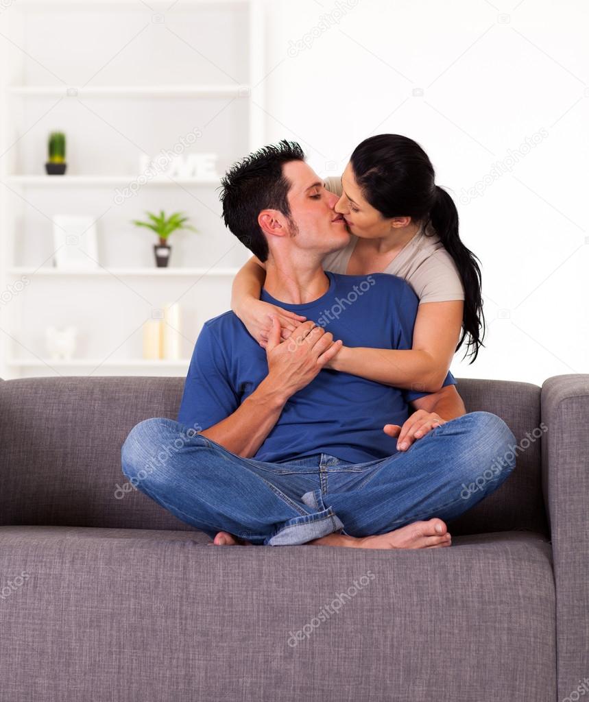 Young couple kissing on sofa at home