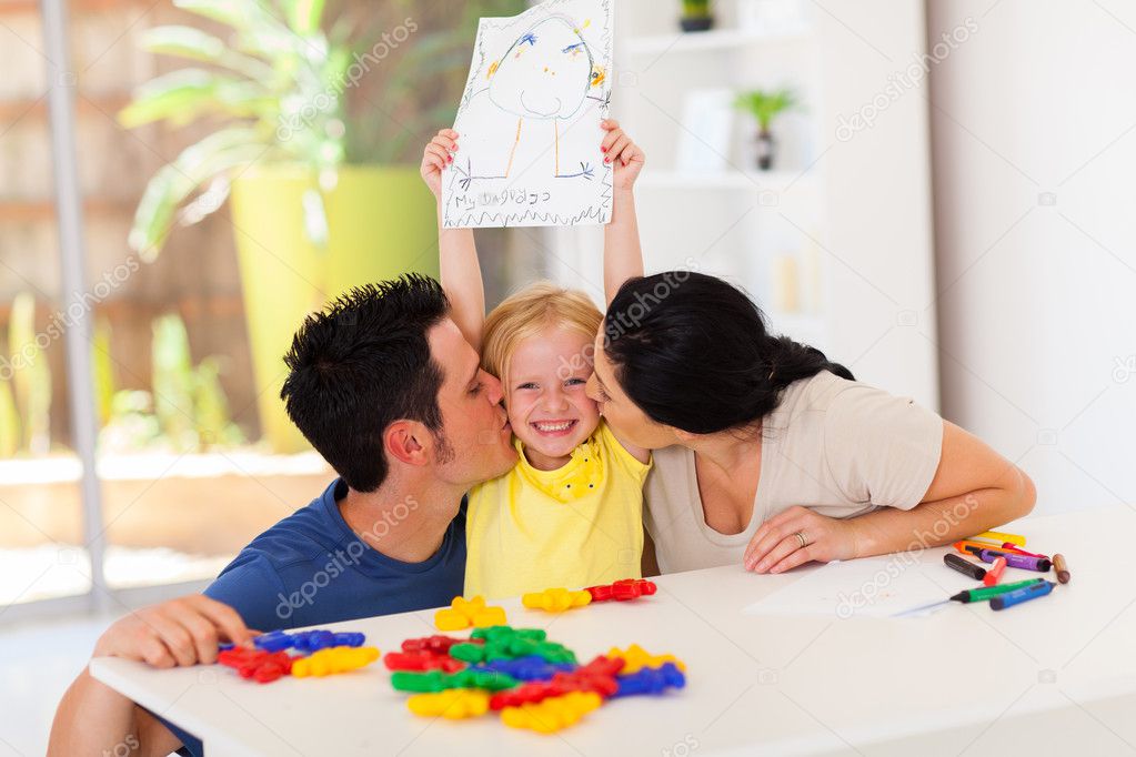 Happy parents kissing cute little daughter with her drawing