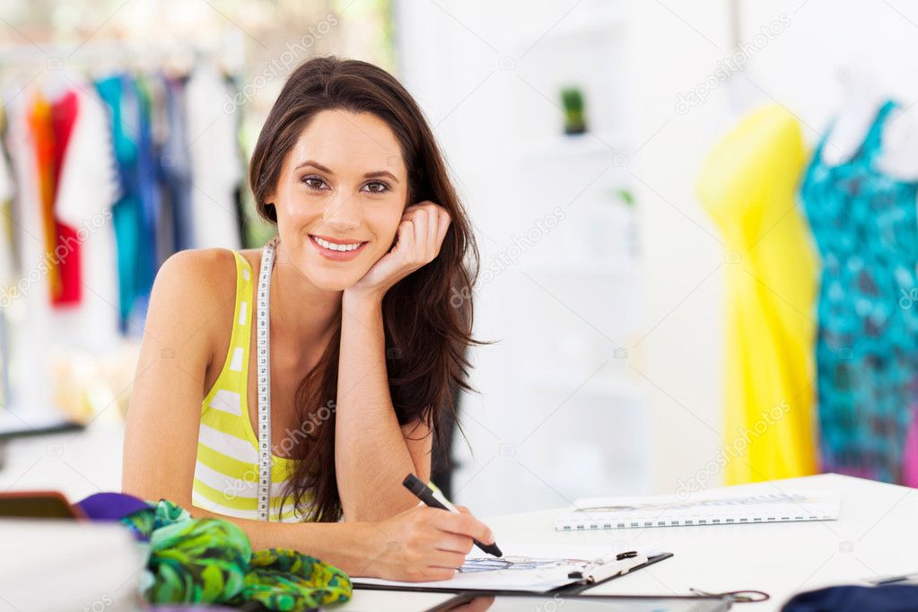 Attractive young female dressmaker sketching in studio