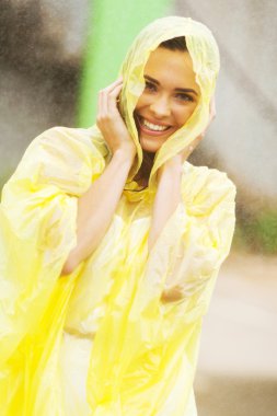 Pretty woman dress in raincoat having fun in the rain clipart