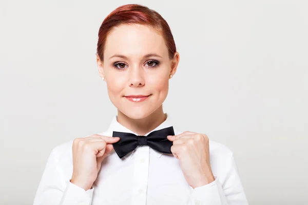 Beautiful young waitress holding bow tie and smiling — Stock Photo, Image