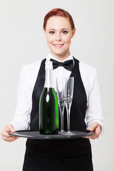 Ganska ung servitris innehar fack med champagne och glas — Stockfoto