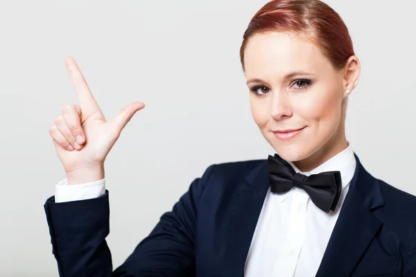 Leuke jonge vrouw in pak met strikje maken hand teken — Stockfoto