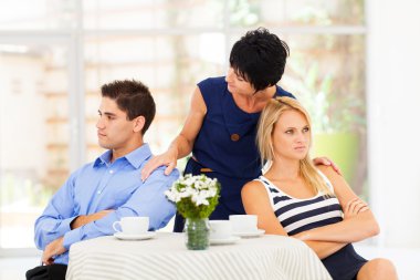 Caring mother reconciling fighting young couple clipart