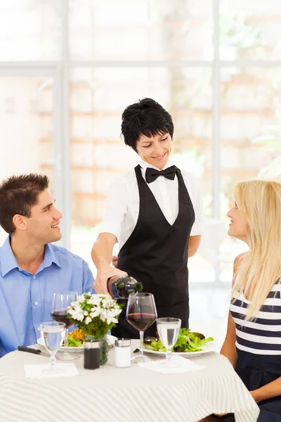 Vriendelijke volwassen serveerster serveren wijn aan diners in restaurant — Stockfoto